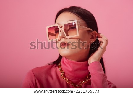 Beautiful fashionable woman wearing trendy pink big square sunglasses, chunky chain, stylish turtleneck. Close up studio portrait. Copy, empty space for text