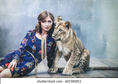 Beautiful fashionable young woman with a cute little alive lion cub