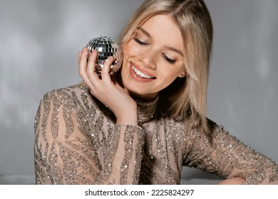 Beautiful Fashionable Young Woman In A Studio Over A Reflective Background, Wearing A Purple Dress, Nice Clothes. Winter Carnival Fashion Photo, Portrait. Blue Gel Light. 