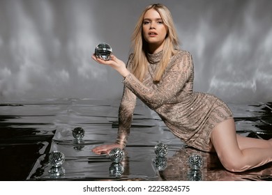 Beautiful Fashionable Young Woman In A Studio Over A Reflective Background, Wearing A Purple Dress, Nice Clothes. Winter Carnival Fashion Photo, Portrait. Blue Gel Light. 