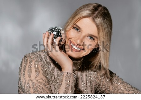 Beautiful fashionable young woman in a studio over a reflective background, wearing a purple dress, nice clothes. Winter carnival fashion photo, portrait. Blue gel light. 