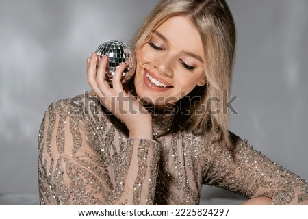 Beautiful fashionable young woman in a studio over a reflective background, wearing a purple dress, nice clothes. Winter carnival fashion photo, portrait. Blue gel light. 