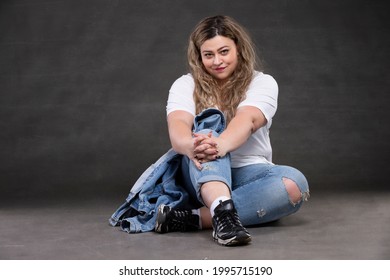 Beautiful Fat Woman In Denim Clothes On A Gray Background. Plus Size Model Girl.