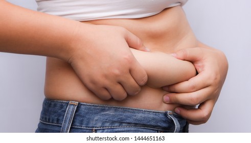 A beautiful fat woman uses second hand to hold the excess wax his stomach  Standing in front the gray background