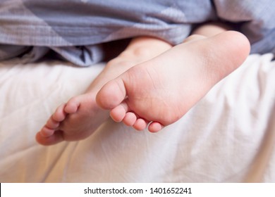 Beautiful Feet Of A Little Cute Child Girl Lying In Bed Close Up.  Sleep And Relax Concept.