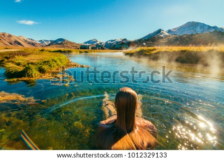 Beautiful female back packer traveler relaxing in the natural hot springs of LANDMANNALAUGAR, Iceland