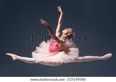 Beautiful female ballet dancer jumping on a gray background. Ballerina is wearing in  pink tutu and pointe shoes