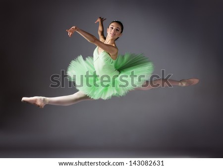 Beautiful female ballet dancer on a grey background. Ballerina is wearing a green tutu and pointe shoes.