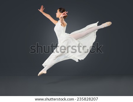 Beautiful female ballet dancer on a grey background. Ballerina is wearing a  tutu and point shoes.