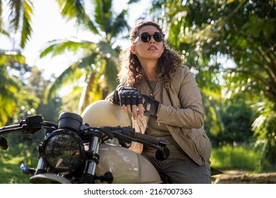 Beautiful female biker driving a cafe' racer motorbike - Pretty girl driving a motorbike and enjoying the roadtrip