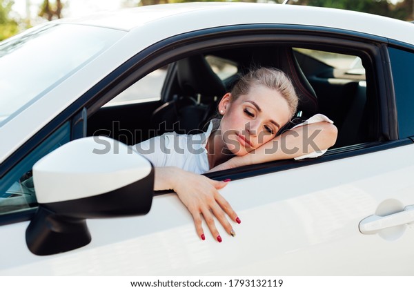 Beautiful female blonde driver behind the wheel of a\
white car