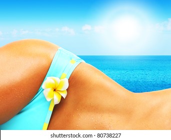 Beautiful female body on the beach, conceptual image of vacation, spa, travel and summertime holidays