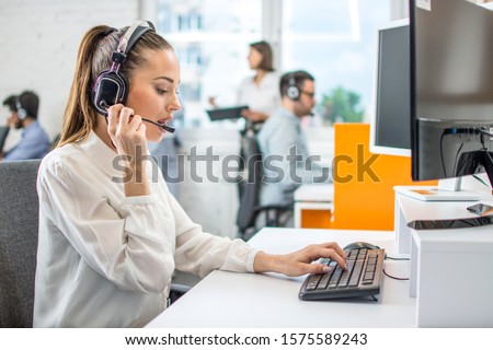 Beautiful female call center operator working on computer in office