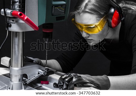 beautiful female carpenter at work using vertical drilling machine. close-up portrait. Photo on black background.