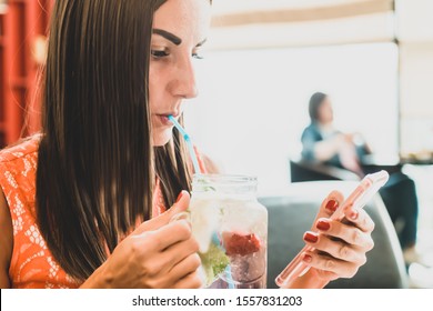 Beautiful Female Chatting On The Phone, Talking On Skype And Drinking A Cocktail, Sitting In A Cafe