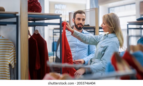 Beautiful Female Customer Shopping In Clothing Store, Retail Sales Associate Helps With Advice. Diverse People In Fashionable Shop, Choosing Stylish Clothes, Colorful Brand With Sustainable Designs