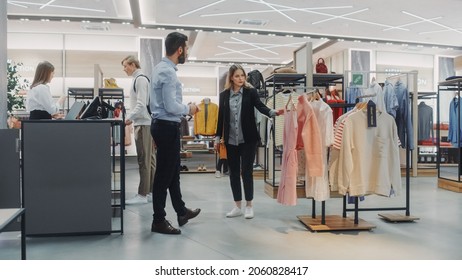 Beautiful Female Customer Shopping In Clothing Store, Retail Sales Associate Helps With Advice. Diverse People In Fashionable Shop, Choosing Stylish Clothes, Colorful Brand With Sustainable Designs