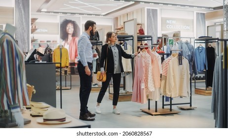 Beautiful Female Customer Shopping In Clothing Store, Retail Sales Associate Helps With Advice. Diverse People In Fashionable Shop, Choosing Stylish Clothes, Colorful Brand With Sustainable Designs