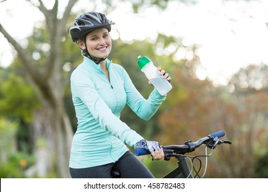 Beautiful female cyclist drinking water in forest at countryside - Powered by Shutterstock