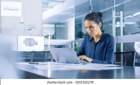 Beautiful Female Data Analyst sitting at the Table Works on a Laptop. Stylish Woman in the Modern Office Environment. - Powered by Shutterstock