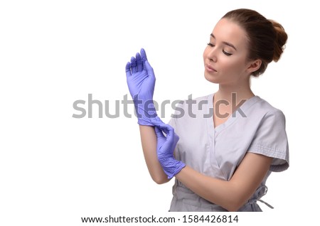 Beautiful female doctor, medical assistant or nurse putting on latex or rubber gloves on white background. Health care concept. Copy space for your text