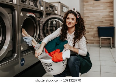 Beautiful female employee working at laundromat shop. - Powered by Shutterstock