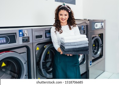Beautiful female employee working at laundromat shop.