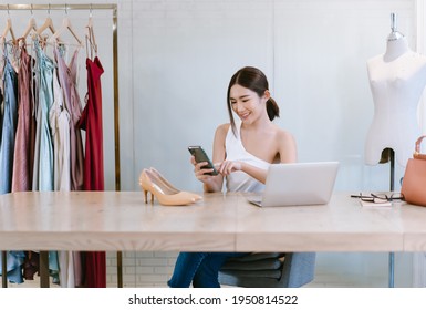 Beautiful Female Entrepreneur. Young Cheerful Asian Woman Fashion Designer Worker Online Banking Smartphone While Sitting On Desk. Startup Small Business Owner, Freelance Work. SME Marketing Concept