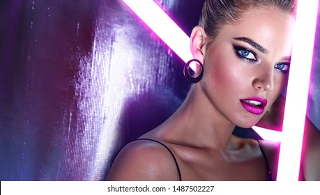 Beautiful female face close-up in neon pink light of bright lamps.Beauty, fashion, silver, sparkles, hairstyle, makeup, glamor, luxury, neon, glow, makeup, bright, model.