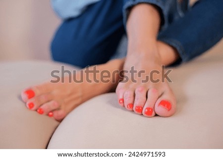 beautiful female feet with long toes and orange nail polish close-up on the sofa