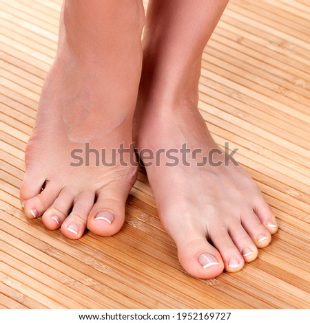 Beautiful female feet on a wooden floor, closeup shot