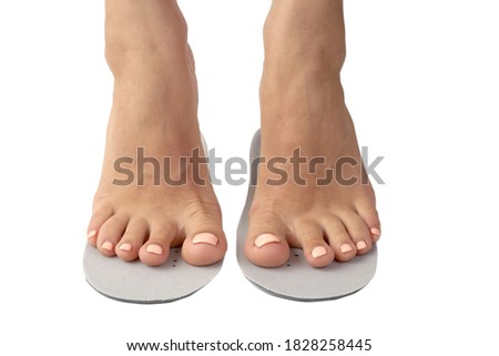 Beautiful female feets and insoles isolated on a white background. The girl tries on orthopedic insoles.