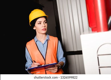 Beautiful Female Firefighter Holding Clipboard And Standing Near Fire Panel 