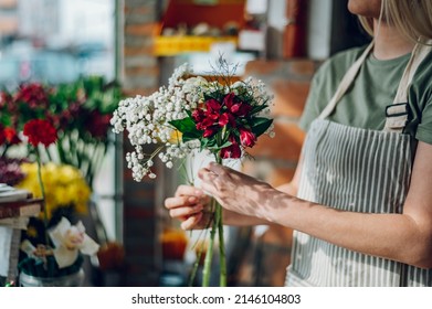 Beautiful female florist creating beautiful bouquet at wooden table in a flower shop. Florist at work. Flowers delivery. Store order and flower design for client. - Powered by Shutterstock