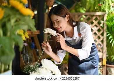 Beautiful female florist smelling white flowers with eyes closed. Business, sale and floristry concept - Powered by Shutterstock