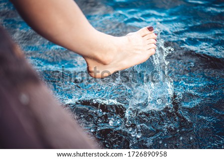 beautiful female foot plays with water and makes splashes in the lake