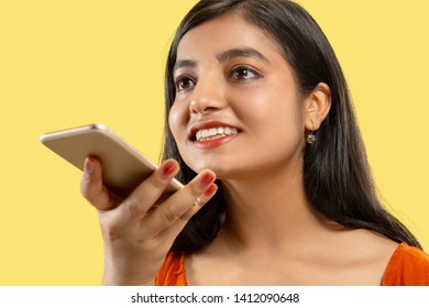 Beautiful Female Half-length Portrait Isolated On Yellow Studio Background. Young Emotional Indian Woman In Dress Talking On The Phone. Negative Space. Facial Expression, Human Emotions Concept.