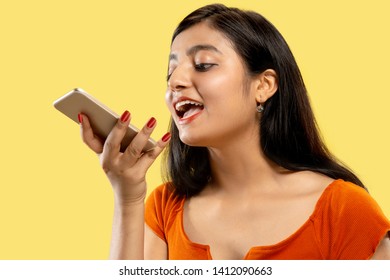 Beautiful Female Half-length Portrait Isolated On Yellow Studio Background. Young Emotional Indian Woman In Dress Talking On The Phone. Negative Space. Facial Expression, Human Emotions Concept.