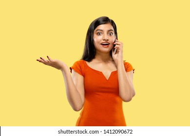 Beautiful Female Half-length Portrait Isolated On Yellow Studio Background. Young Emotional Indian Woman In Dress Talking On The Phone. Negative Space. Facial Expression, Human Emotions Concept.