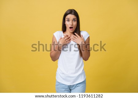 Beautiful female half-length portrait isolated on yellow studio backgroud. The young emotional smiling and surprised woman standing and looking at camera.The human emotions, facial expression concept