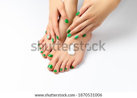 Beautiful female hand apply cream on her foot. Green spring summer manicure pedicure nail design. Beauty treatment concept
