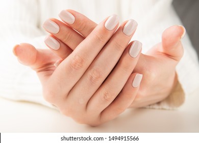 Beautiful female hand with beige nail design.