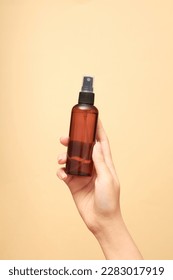 Beautiful female hand holding an empty bottle without label on beige background. Mockup for cosmetic spray bottle such as mineral spray or hair spray. Front view, space for design. - Shutterstock ID 2283017919