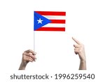 A beautiful female hand holds a Puerto Rico flag to which she shows the finger of her other hand, isolated on white background.