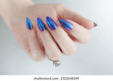 hermosa mano femenina con uñas largas, manicura púrpura y azul 