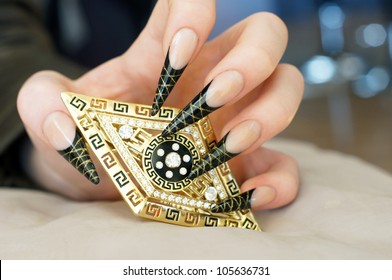 Beautiful Female Hand With Stunning Black And Gold Decorative French Stiletto Nail Art Design Holding Golden Hair Clip