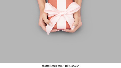 Beautiful Female Hands With Gentle Manicure Hold In Their Hands A Beautiful Gift On A Ultimate Gray Background. Holidays. Color Trend Concept. Fashionable Pantone Color Of The Year 2021.