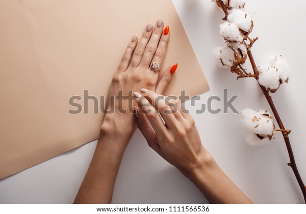 beautiful female hands with gold\
ring on index finger on beige and white background. with\
cotton