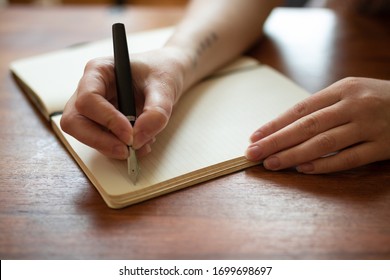 Beautiful female hands writing a journal entry in a diary using an ink fountain pen.
