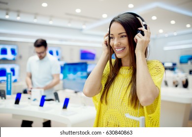 Beautiful Female Listening Music, Having Headphones At Tech Store. Shopping Concept.